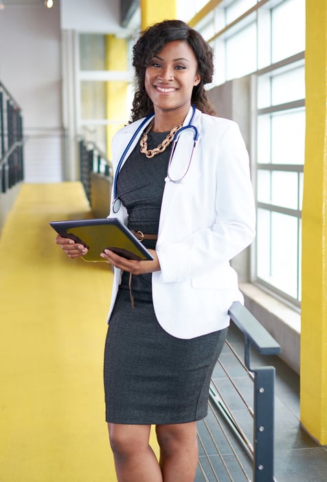 Portrait of a female doctor holding her patient chart on digital tablet in bright modern hospital